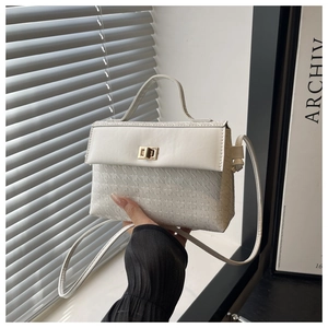 Detail of white Kelly bag with houndstooth texture and golden twist-lock closure
