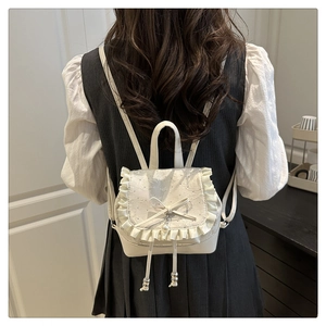 Mini white backpack with lace embroidery and bow pearl pendant detail on model