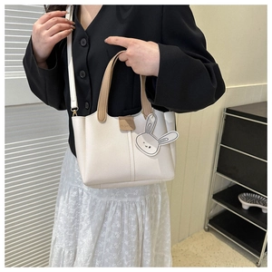 Detail of minimalist bucket bag showing PU leather texture and cute fashion rabbit pendant