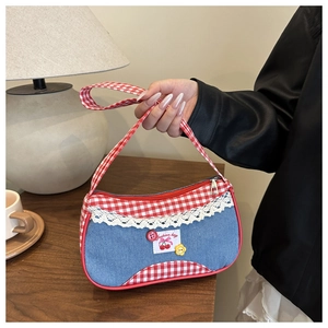 Detail of blue denim and red gingham tote bag featuring cherry patch and white lace trim