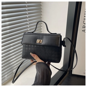 Detail of black tote bag with textured lower panel and gold metallic twist lock closure
