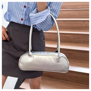 Close-up of metallic silver baguette bag worn by model on wooden stairs