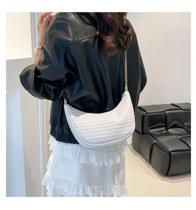 Detail of woven texture and gold chain strap on a white crescent shoulder bag