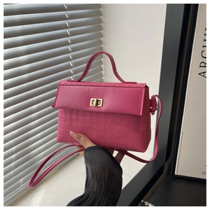 Close-up of rose pink kelly bag with geometric embossed texture and gold twist lock