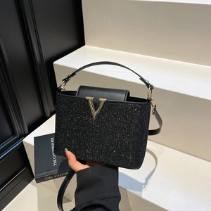Sac à main élégant à paillettes noires avec boucle en V dorée sur décor minimaliste