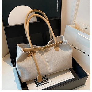 Detailed top view of large cream canvas tote with tan leather straps and vertical stitching