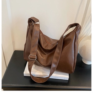 Détail d'un sac bandoulière en cuir PU marron foncé avec sangle réglable et boucle