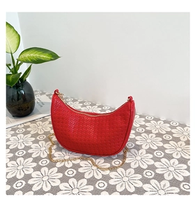 Detailed shot of red woven half-moon bag with golden chain strap and rich texture