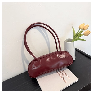 Detail view of the deep red faux leather baguette bag with slender long handles