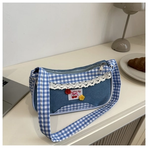 Close-up of blue denim bag featuring white lace trim and a cherry patch detail