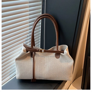 Detail of canvas tote bag showing brown leather handles and textured weave material