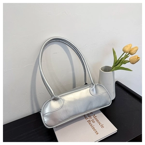 Detail of silver metallic baguette bag with long handles styled on a modern table setup