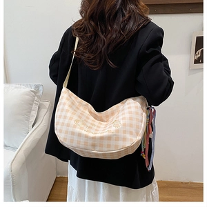 Detail of checkered canvas half-moon bag with gold embroidery and colorful ribbon strap