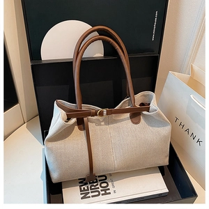 Detail of canvas tote bag with leather handles and decorative belt buckle on front