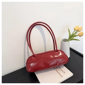 Close-up of vibrant red patent leather bag on a desk with tulips and a magazine