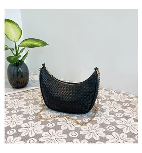 Close-up of black woven leather crescent bag with elegant gold chain strap detail