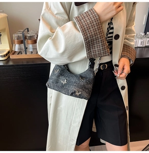 Detail of dark gray denim shoulder bag with four silver butterfly metal charms