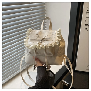 Detail view of cream ruffle mini backpack with decorative bow and pearl pendant charm