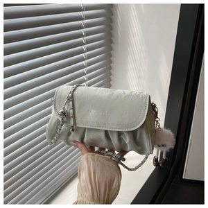 Detail of mint green pleated shoulder bag with chain strap and fluffy charm