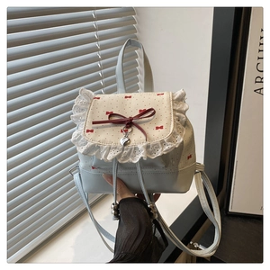 Detail of light blue mini backpack with red polka dot bow, lace trim, and heart pendant