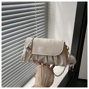 Detail of cream pleated crossbody bag with silver chain and cute plush pendant