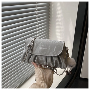 Detail of silver pleated crossbody bag with chain strap and soft plush charm pendant