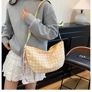 Detailed embroidery and rainbow ribbon on a yellow plaid canvas crescent bag