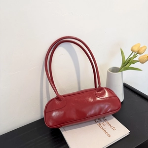 Minimalist red patent leather baguette bag with dual shoulder straps in a chic home setting