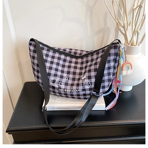 Close-up of vintage plaid underarm bag featuring heart embroidery and rainbow pendant