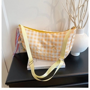 Detail of yellow plaid crescent bag featuring embroidery and adjustable strap