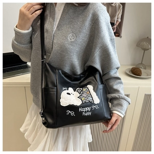 Detail of black leather shoulder bag featuring a cute white puppy embroidery and side pocket