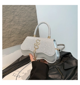 Détail du sac à main argenté à paillettes avec pompon logo S et base ondulée unique