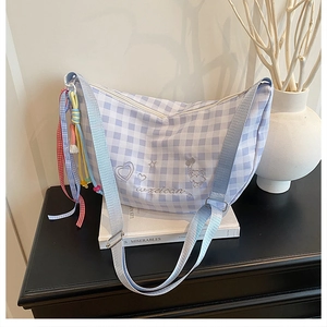 Detail of blue plaid crescent bag featuring embroidery and colorful tassel charm