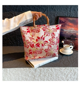 Detailed macro view of the double-sided embroidery and classic bamboo handle on the tote bag