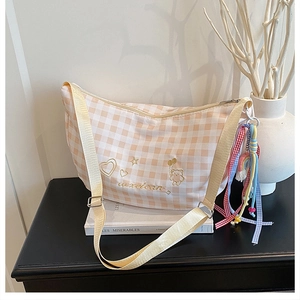 Detail of checkered canvas bag featuring bear embroidery and colorful ribbon accents