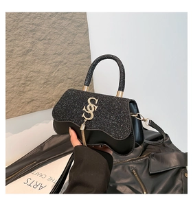 Détail du rabat à paillettes noires sur sac de luxe avec fermoir S doré et glands
