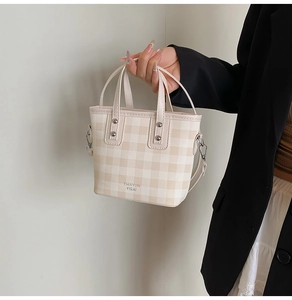 Close-up of a plaid crossbody bucket bag with beige gingham pattern and sturdy handles