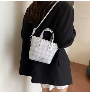 Detail of grey checkerboard mini tote bag with silver rivets and detachable shoulder strap