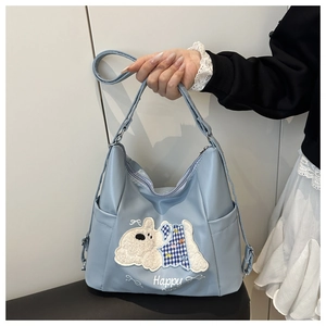 Detail of light blue shoulder bag featuring a cute puppy embroidery and plaid patterns