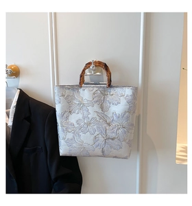Close-up of floral jacquard fabric and natural bamboo handle on a tote bag