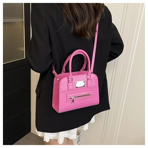 Hot pink mini tote bag with silver zippers shown on a model in a black blazer