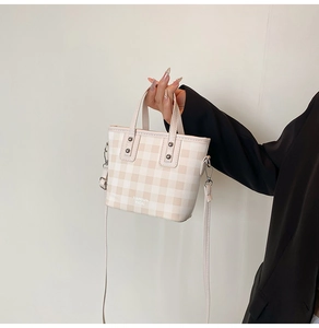 Detail of checkered crossbody bag with silver rivet handle and adjustable shoulder strap