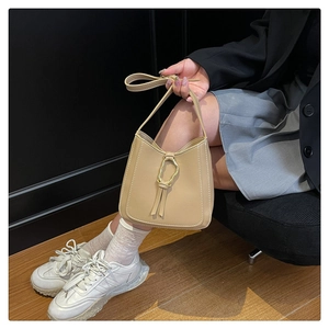 Detail of beige PU shoulder bag featuring unique gold metal ring and decorative straps