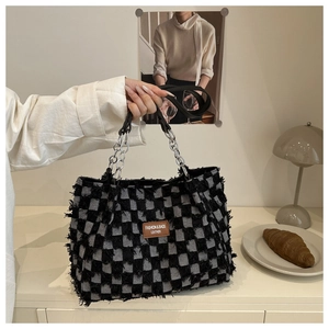 Detail of frayed checkerboard tote bag featuring silver chain straps and leather label