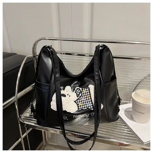 Detail of black PU leather shoulder bag featuring a cute white puppy embroidery design