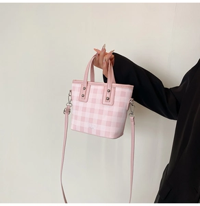 Detail of pink and white checkered mini tote bag featuring metal rivets and leather handle