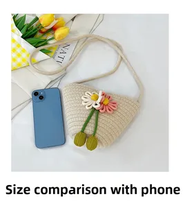 Mini-Strandtasche aus geflochtener Baumwolle mit Blumen neben einem Smartphone