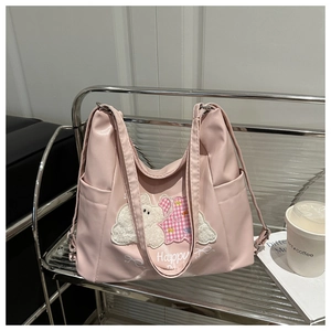 Close-up of pink PU leather tote bag with cute animal embroidery and Happy print detail