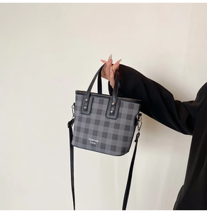 Detail of the checkered leather handbag featuring metal rivets and detachable shoulder strap