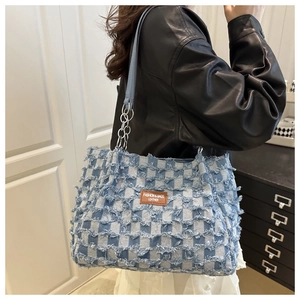 Détail du sac hobo en jean à carreaux bleus avec bords effilochés et logo en cuir